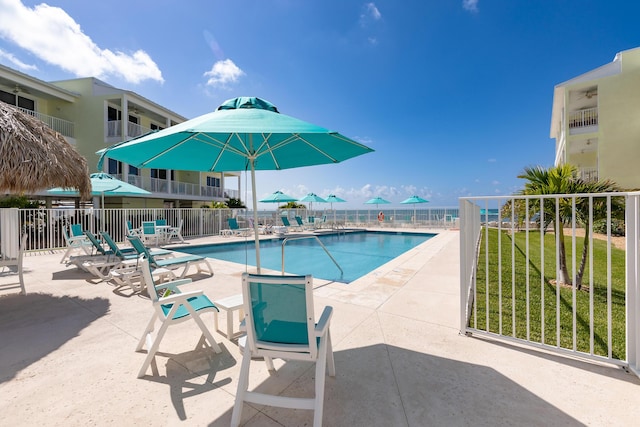 community pool featuring a lawn, a patio area, and fence