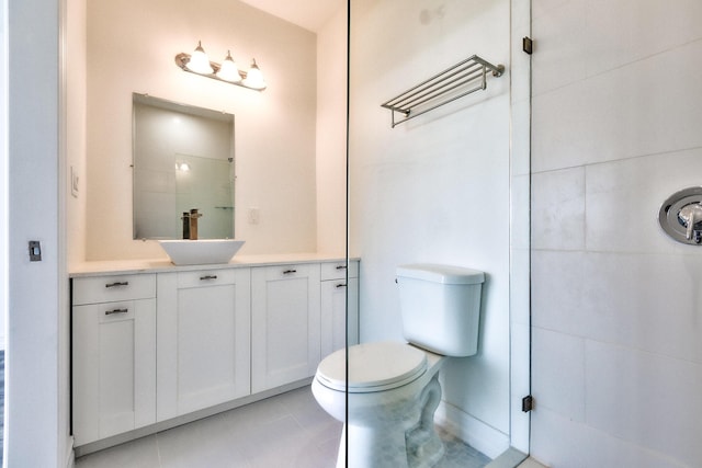 bathroom featuring toilet, tile patterned floors, tiled shower, and vanity