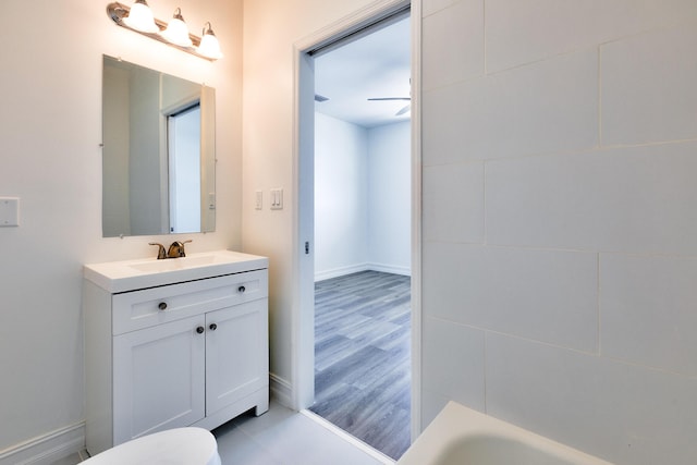 bathroom with vanity, baseboards, ceiling fan, and a tub