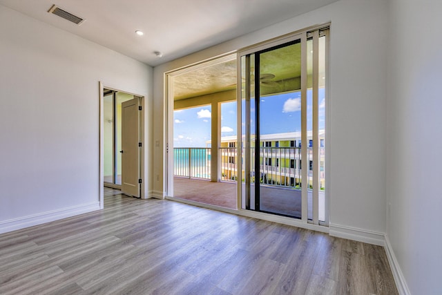 empty room with baseboards, wood finished floors, and visible vents