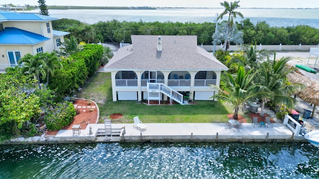 rear view of property with a patio, a water view, a lawn, and a sunroom