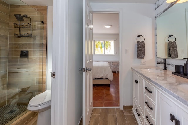 bathroom with vanity, toilet, and tiled shower