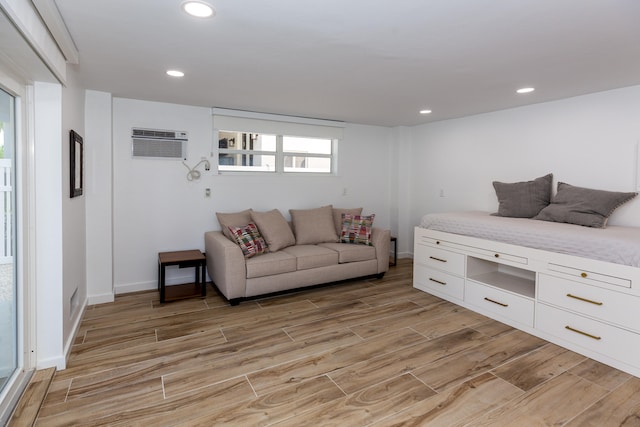 living room with a wall mounted AC and light wood-type flooring