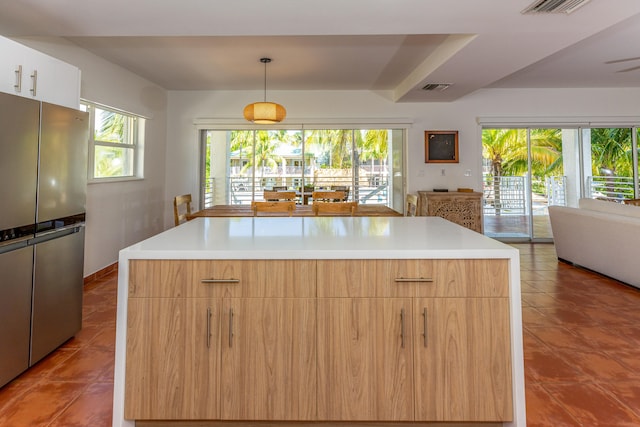 kitchen with a healthy amount of sunlight, a center island, pendant lighting, and stainless steel refrigerator