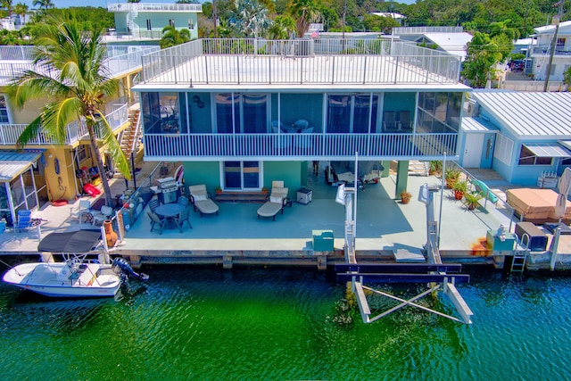 rear view of house with a patio area, a sunroom, and a water view