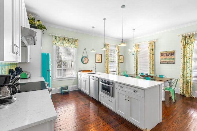 kitchen with wall chimney exhaust hood, white cabinetry, light stone counters, hanging light fixtures, and stainless steel appliances