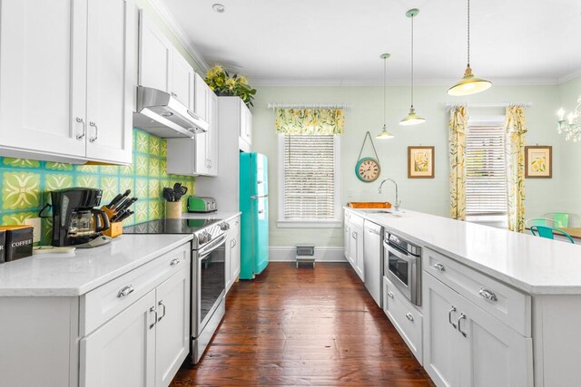 kitchen with appliances with stainless steel finishes, sink, pendant lighting, and white cabinets