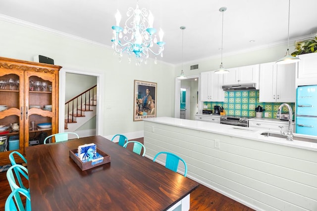 dining space featuring dark hardwood / wood-style flooring, sink, a notable chandelier, and ornamental molding