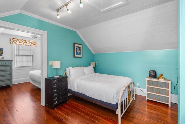 bedroom featuring track lighting, dark hardwood / wood-style floors, and vaulted ceiling