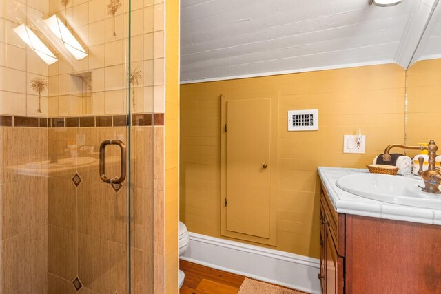 bathroom with hardwood / wood-style floors, an enclosed shower, vanity, ornamental molding, and toilet