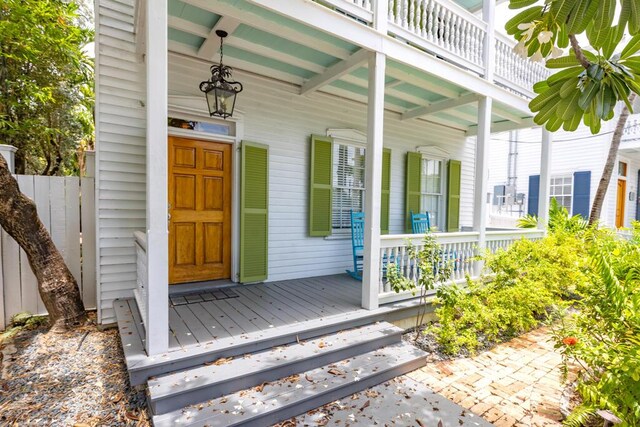 view of exterior entry with a balcony and a porch