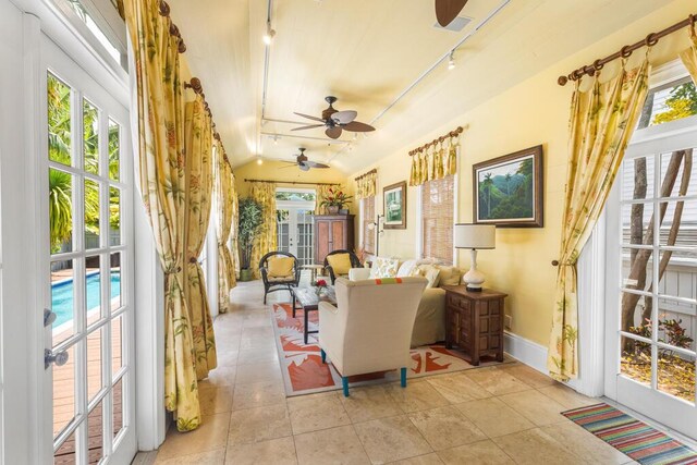 sunroom / solarium featuring ceiling fan, rail lighting, and vaulted ceiling