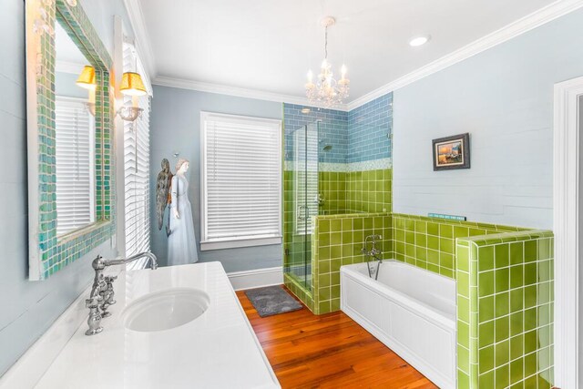 bathroom featuring shower with separate bathtub, ornamental molding, vanity, a notable chandelier, and hardwood / wood-style floors