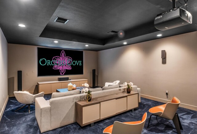 home theater room featuring dark carpet and a tray ceiling