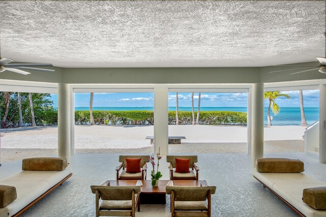 interior space with a textured ceiling, ceiling fan, and a water view