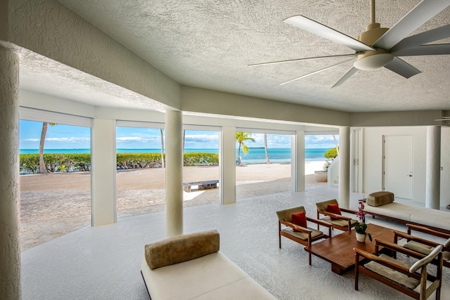 interior space featuring ceiling fan, a water view, and a textured ceiling