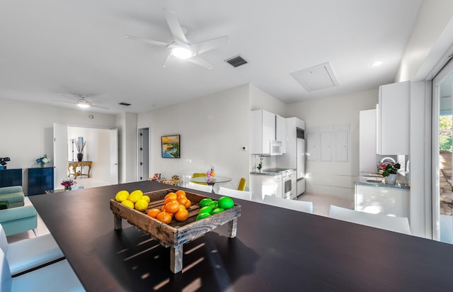 kitchen with ceiling fan, white appliances, kitchen peninsula, and white cabinets