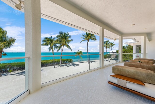 interior space featuring a water view, a beach view, and a textured ceiling