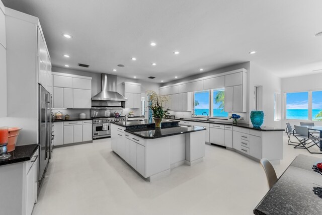 kitchen featuring a large island, premium appliances, white cabinetry, and wall chimney exhaust hood