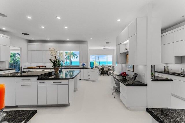 kitchen featuring dark stone countertops, sink, and white cabinets