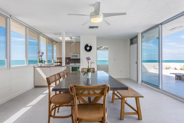 dining room featuring a view of the beach, a healthy amount of sunlight, and a water view