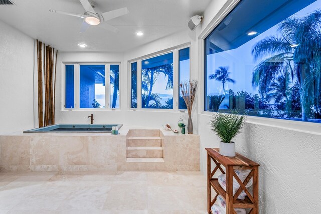 bathroom featuring a relaxing tiled tub and ceiling fan