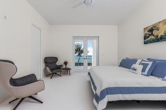 bedroom featuring ceiling fan, access to exterior, a water view, carpet floors, and french doors