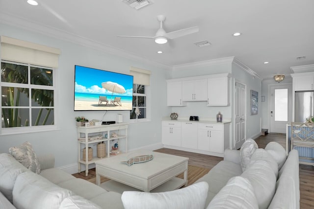 living area with ornamental molding, recessed lighting, visible vents, and wood finished floors