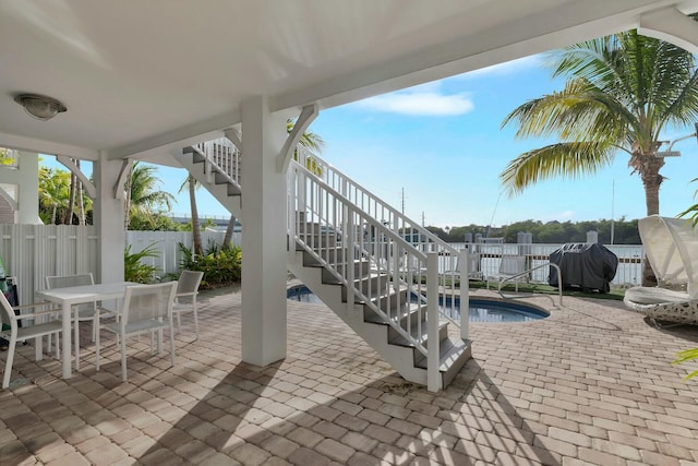 view of pool with a fenced in pool, a patio, stairway, outdoor dining space, and a fenced backyard