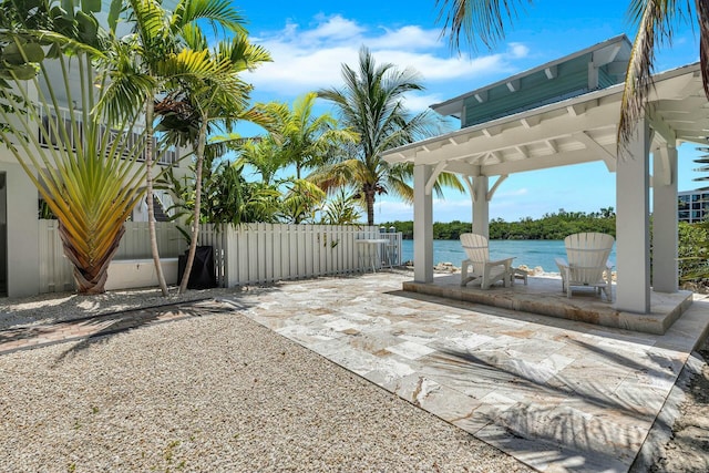 view of patio / terrace featuring a water view and fence