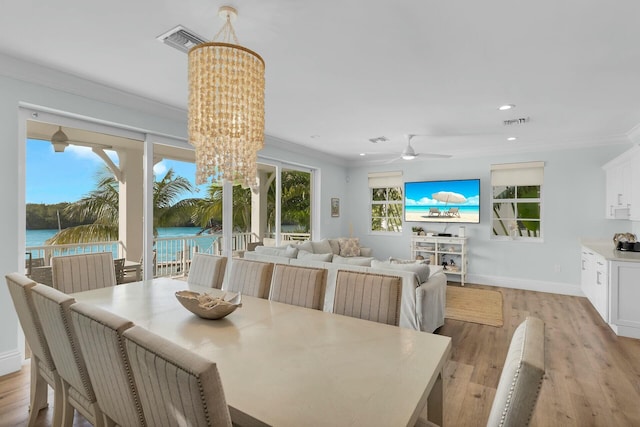 dining area with a healthy amount of sunlight, a water view, visible vents, and crown molding
