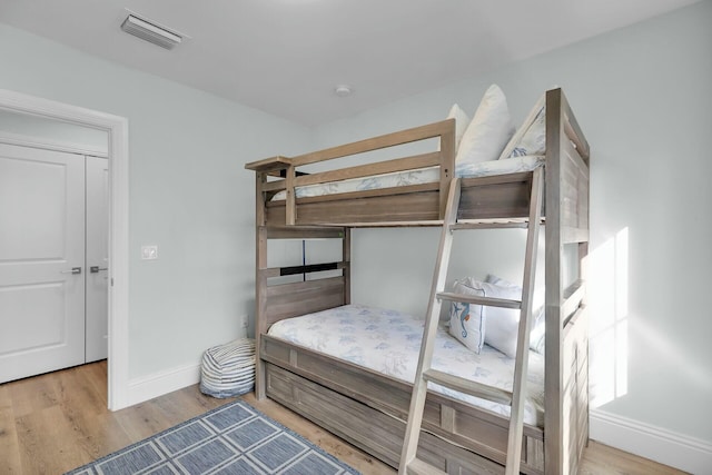 bedroom featuring light wood-style flooring, visible vents, and baseboards