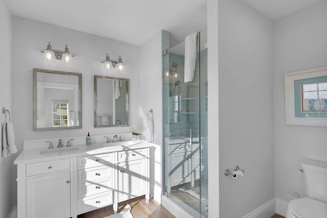 bathroom with double vanity, a stall shower, a sink, and toilet