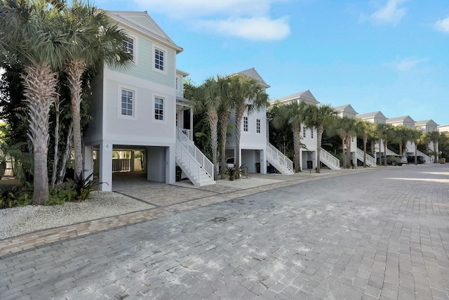 view of front of home with stairs, a carport, decorative driveway, and a residential view