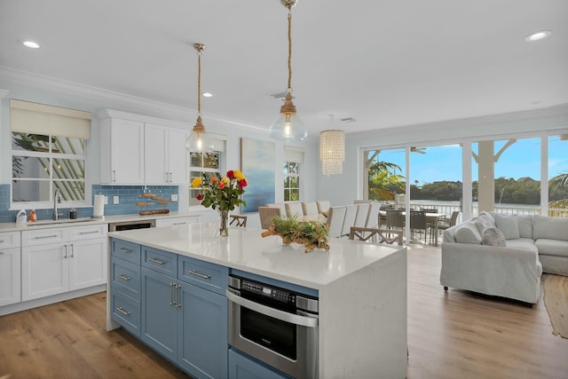 kitchen featuring open floor plan, white cabinetry, light countertops, and decorative light fixtures