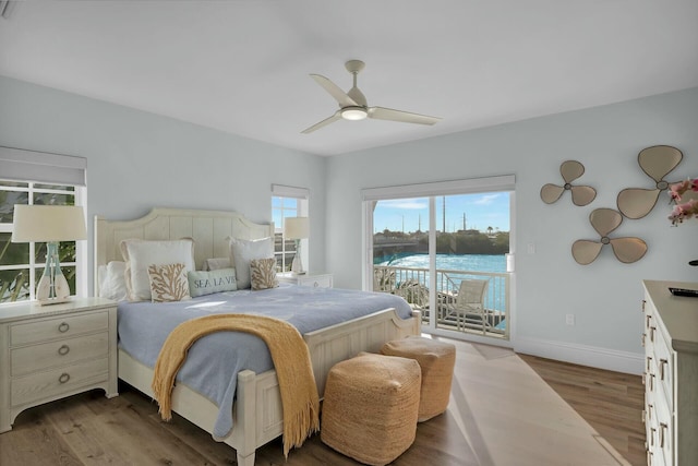bedroom featuring access to outside, a water view, ceiling fan, light wood-type flooring, and baseboards