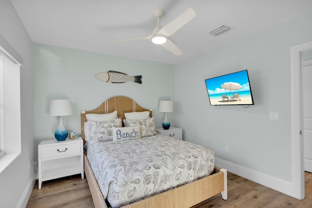 bedroom with baseboards, visible vents, and wood finished floors