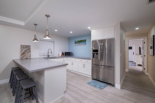 kitchen featuring a kitchen bar, sink, white cabinetry, kitchen peninsula, and stainless steel appliances