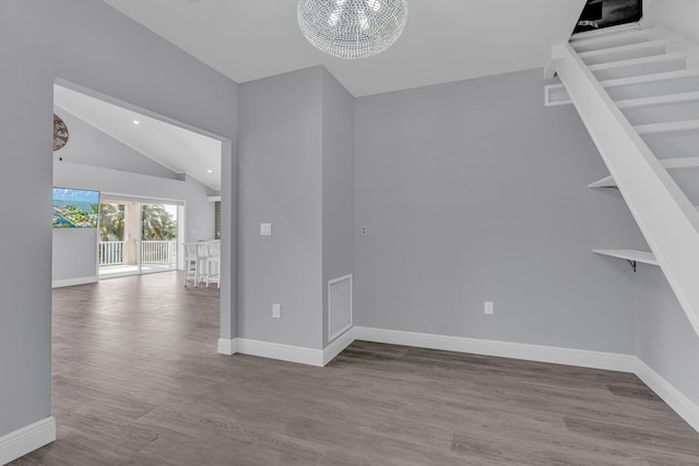 unfurnished room with vaulted ceiling, a notable chandelier, and light wood-type flooring