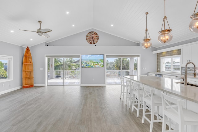 kitchen featuring pendant lighting, sink, white cabinetry, a kitchen breakfast bar, and a healthy amount of sunlight