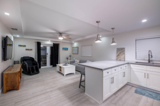 kitchen with pendant lighting, sink, a breakfast bar area, white cabinetry, and kitchen peninsula