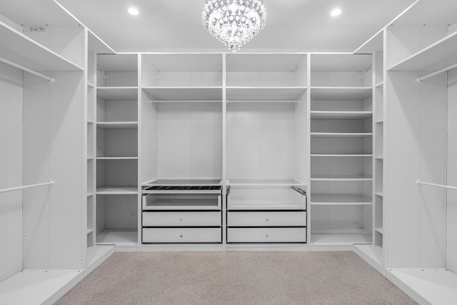 walk in closet featuring an inviting chandelier and carpet flooring