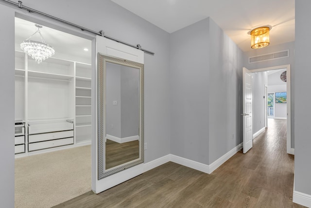 hall with a barn door, hardwood / wood-style floors, and a notable chandelier