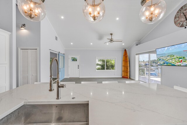 kitchen with ornamental molding, high vaulted ceiling, light stone countertops, and sink