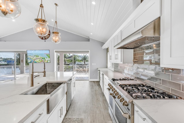 kitchen featuring light stone counters, hanging light fixtures, appliances with stainless steel finishes, white cabinets, and exhaust hood