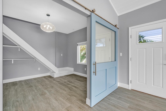 foyer entrance with a barn door, a chandelier, and light hardwood / wood-style floors