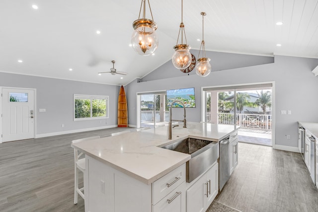 kitchen featuring pendant lighting, white cabinets, a kitchen island with sink, stainless steel dishwasher, and light stone counters