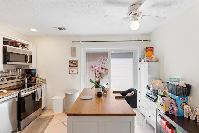 3397 Northside Dr Unit 4, Key West, FL 33040 - kitchen with stainless steel appliances, light tile patterned floors, wooden counters, a ceiling fan, and white cabinetry