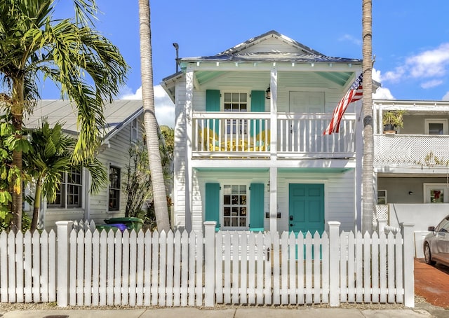 view of front facade with a porch, a fenced front yard, and a balcony