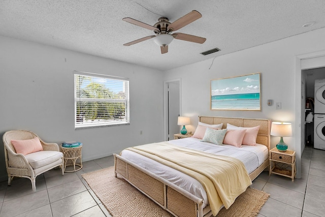 40 High Point Rd Unit F-206, Tavernier, FL 33070 - bedroom with stacked washing machine and dryer, light tile patterned floors, a textured ceiling, and a ceiling fan